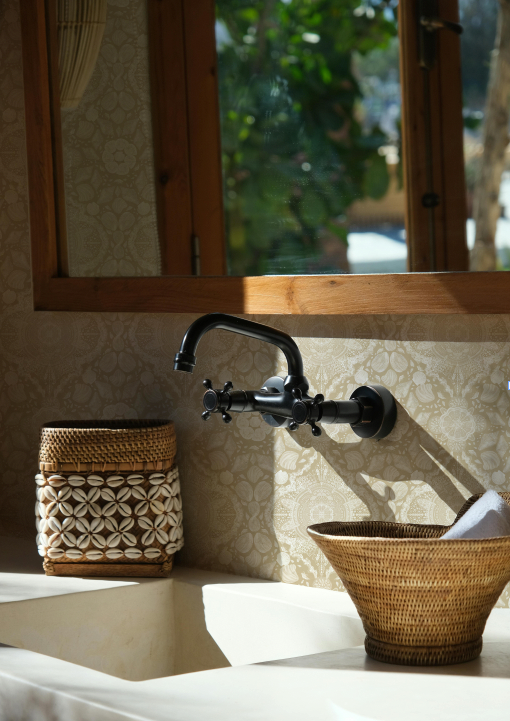 Bathroom setting with a rustic faucet and baskets on a countertop.