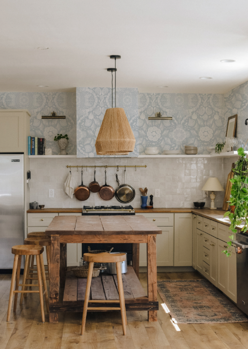 Kitchen with wooden island, stools, and patterned wallpaper
