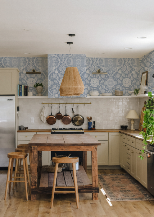 Kitchen with wooden table, stools, and decorative wallpaper.