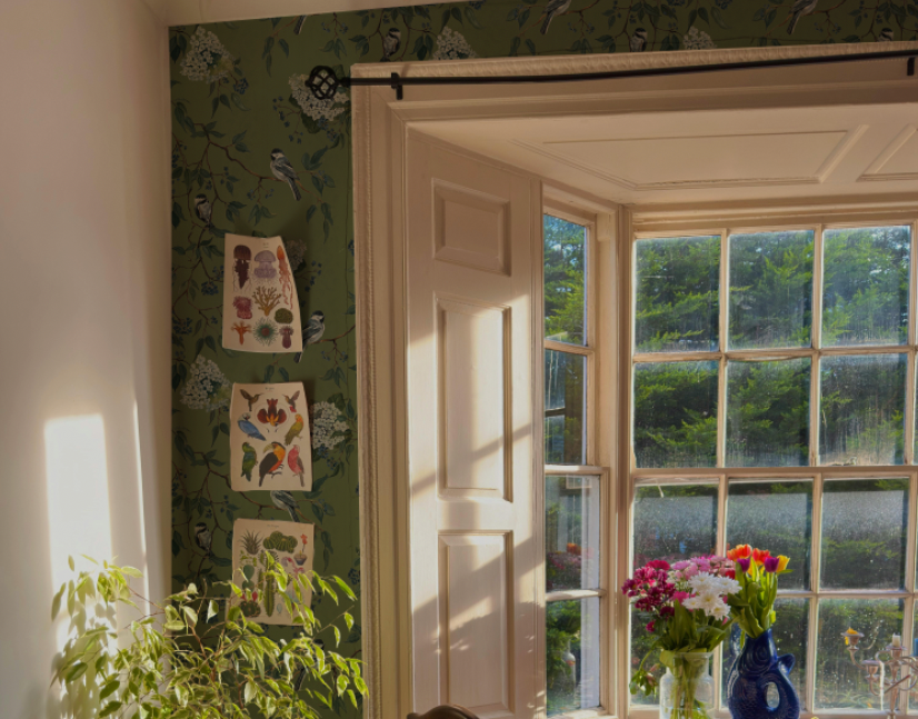 Room interior with floral wallpaper, window, and decorative items.