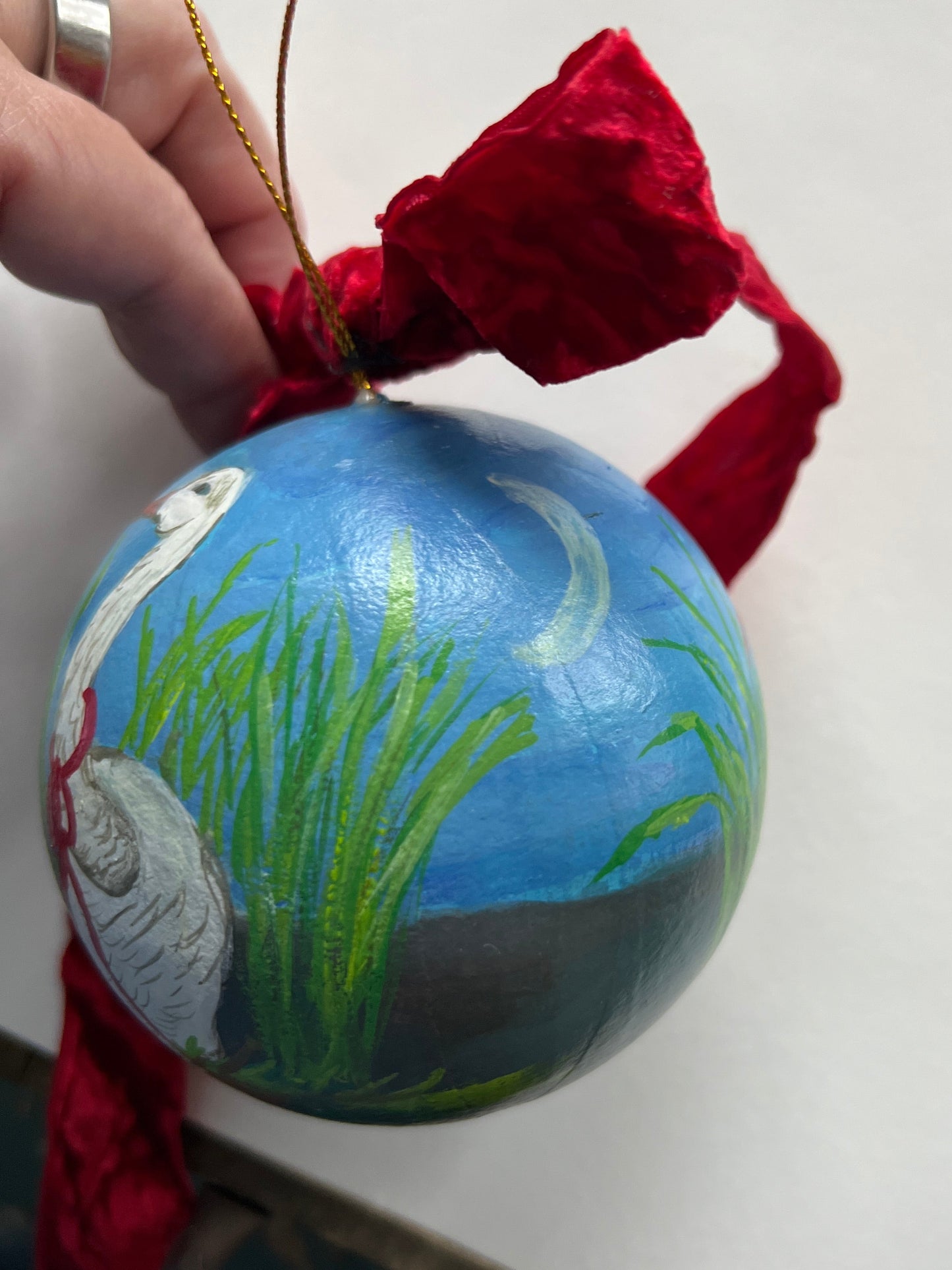 Decorative ornament resembling a globe with a red ribbon on a white background