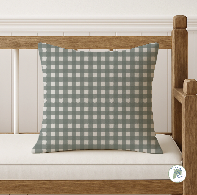 Green and white checkered pillow on a wooden bench with a white background