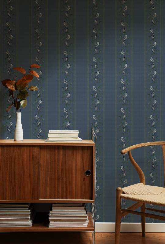 Room interior with wooden cabinet, books, and a chair against a blue wall with decorative patterns.