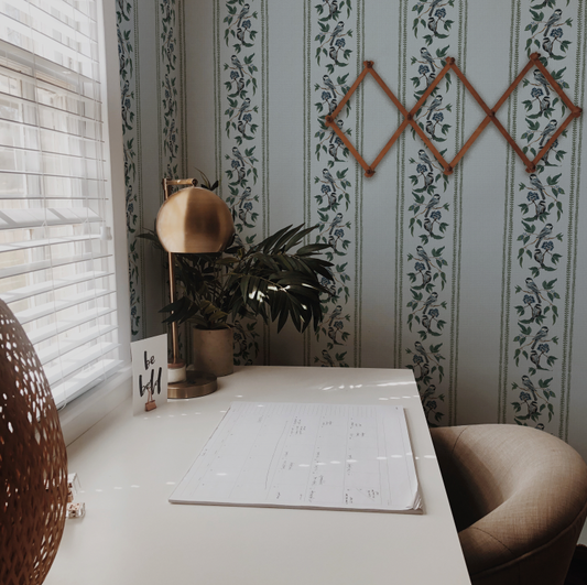 Home office with a desk, plant, and decorative wall art.