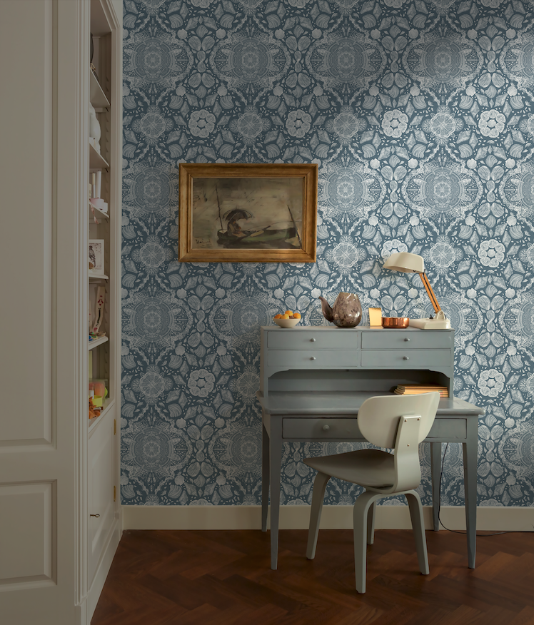 Room with blue patterned wallpaper, desk, and chair.