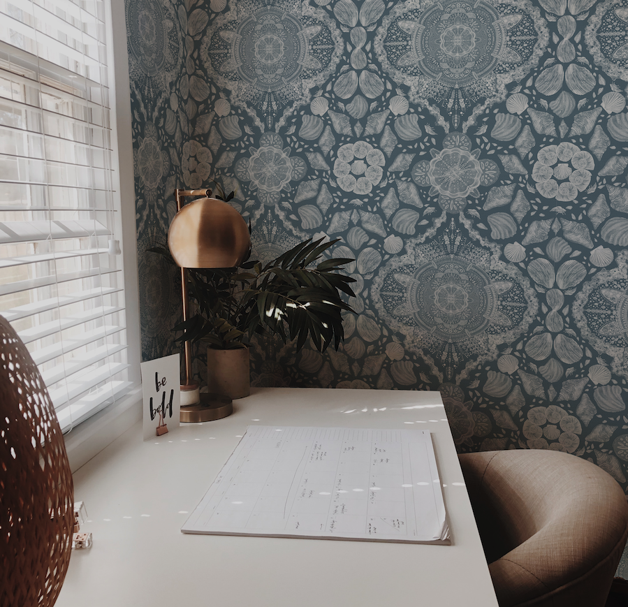 Decorative room with patterned wallpaper, plant, and calendar on a table.