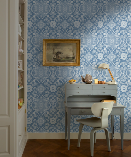Room with blue patterned wallpaper, desk, and chair.