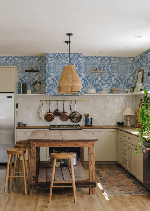 Kitchen with wooden island, stools, and blue patterned wallpaper