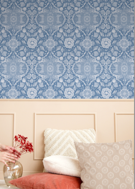 Decorative blue patterned wallpaper with a bed and pillows in the foreground