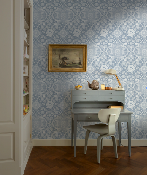 Room interior with a desk, chair, and decorative wall art against a patterned wallpaper.