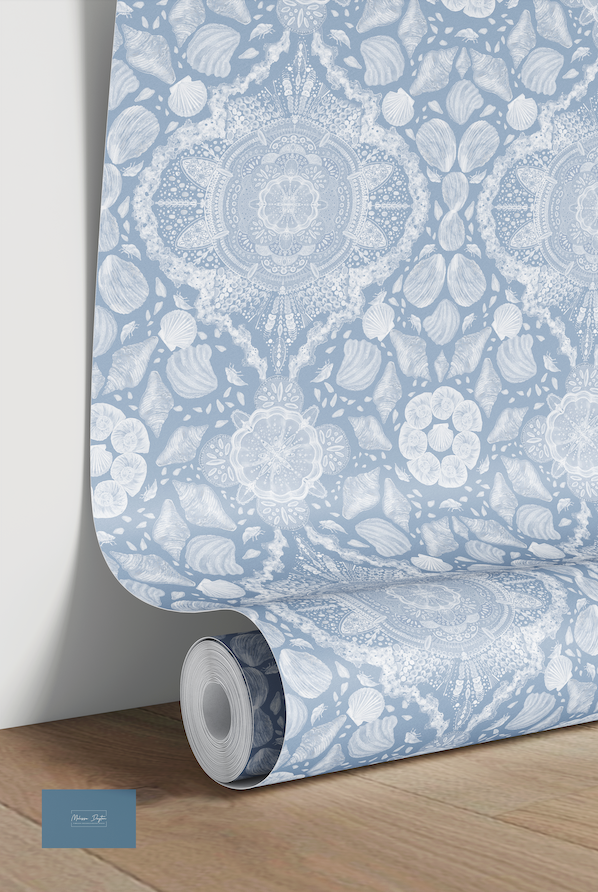 Roll of wallpaper with a blue and white floral pattern on a wooden floor.