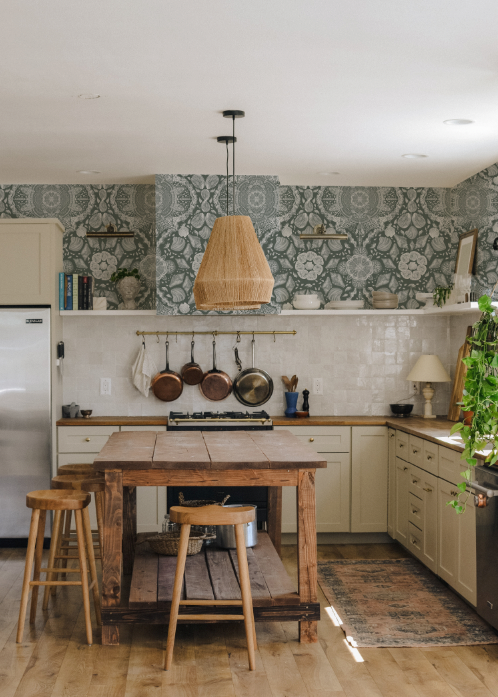 Kitchen with wooden island, stools, and decorative wallpaper.
