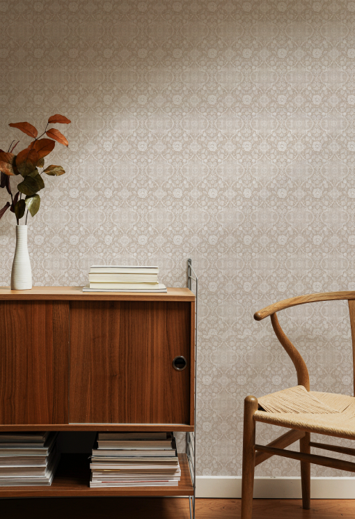 Wooden sideboard with a vase of flowers and books against a patterned wall.