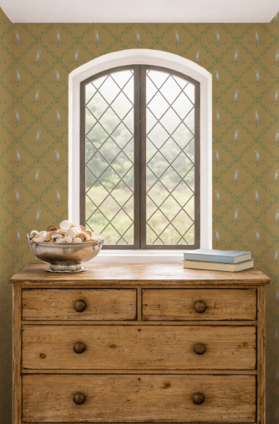 Wooden dresser with a bowl of seashells and books against a green patterned wall.
