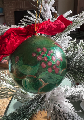 Decorative green ornament with floral design on a Christmas tree.