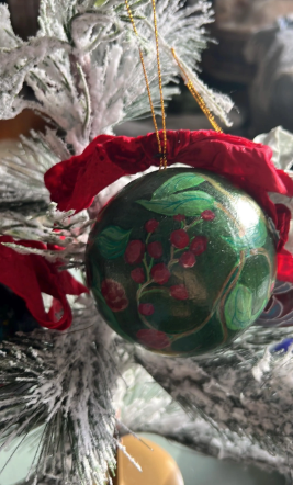 Decorative Christmas ornament with green and red design on a tree.