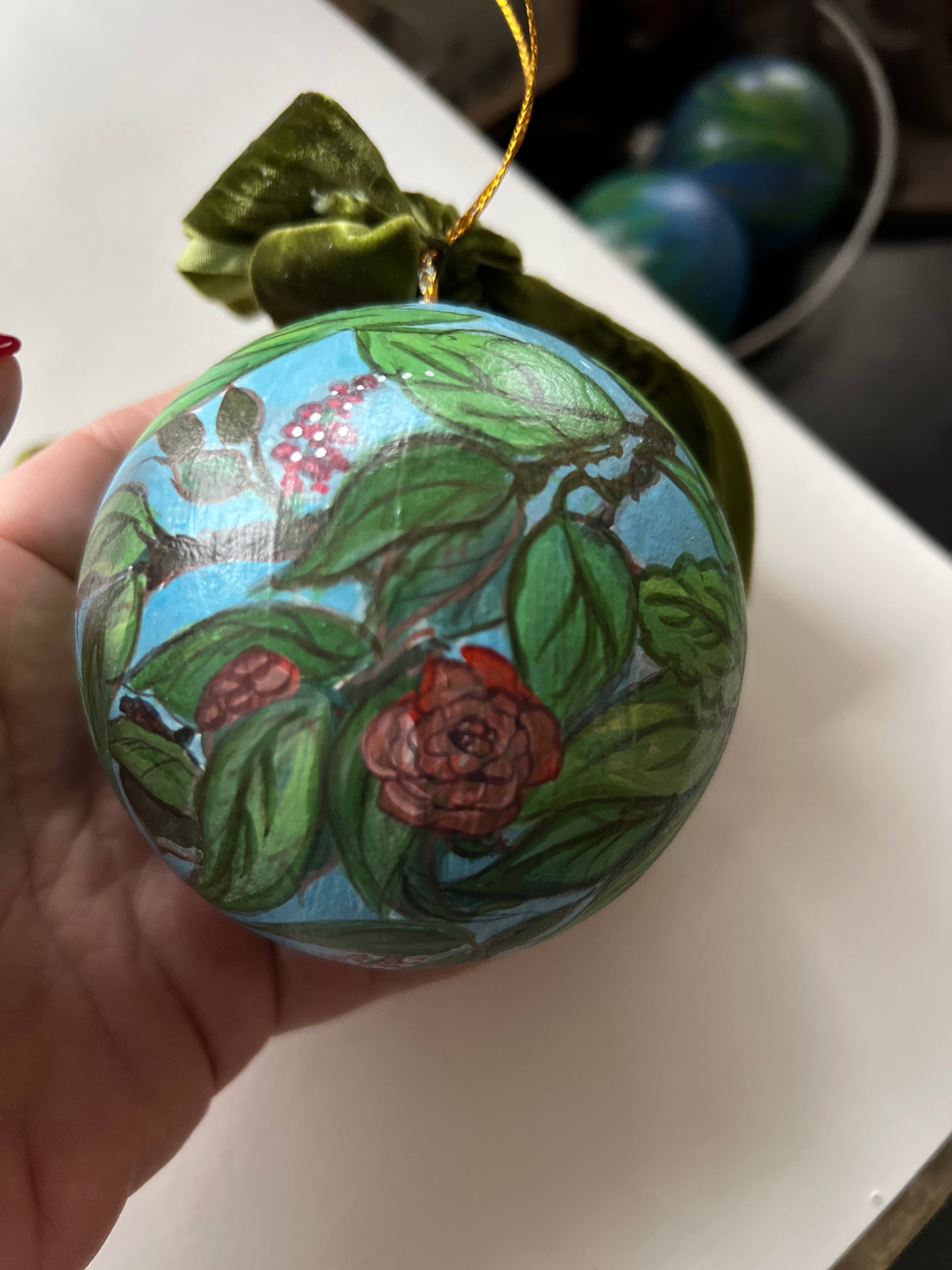 Decorative round object with floral design held by a hand on a white surface