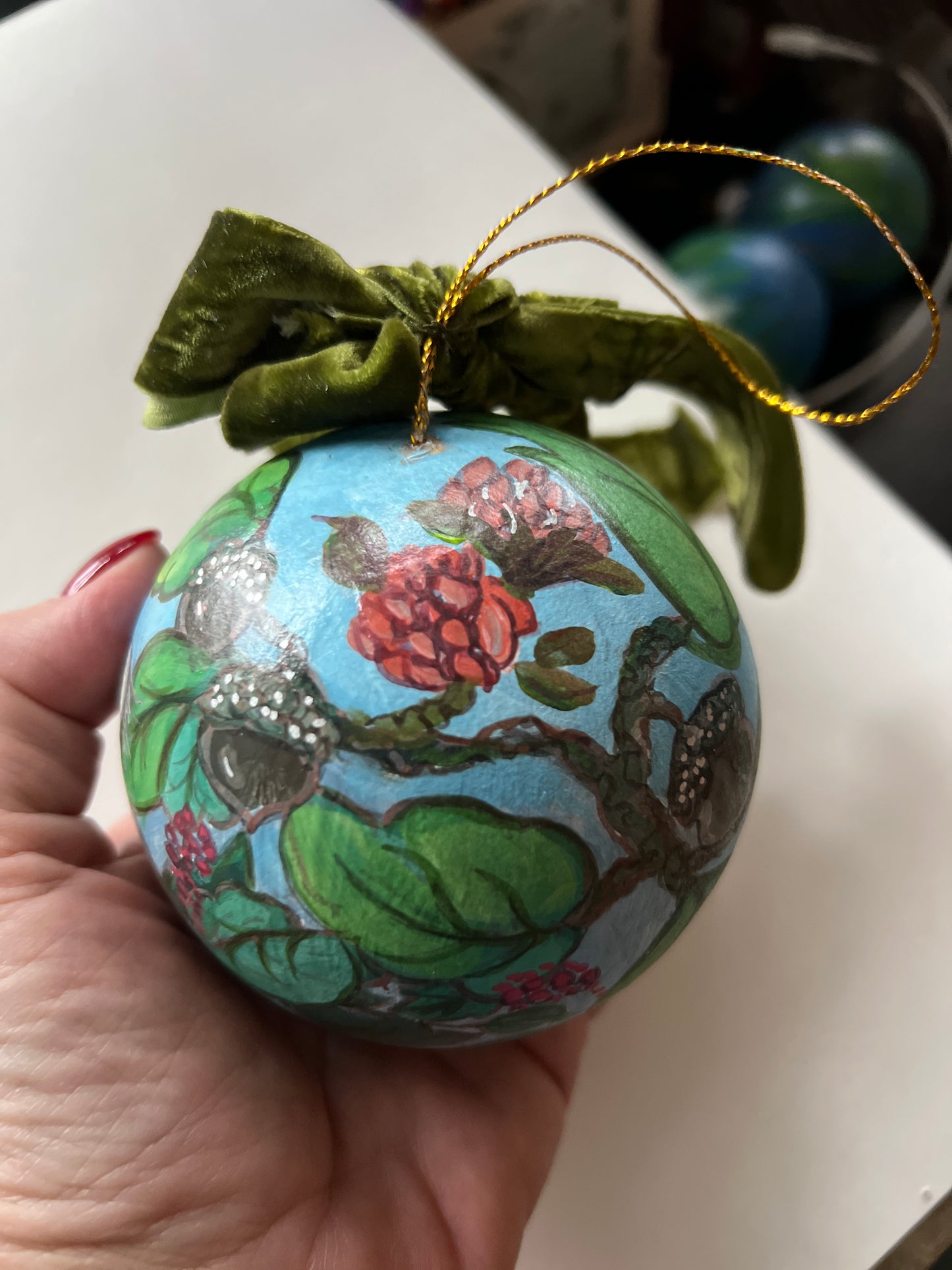Decorative ornament with floral design held by a hand on a white surface