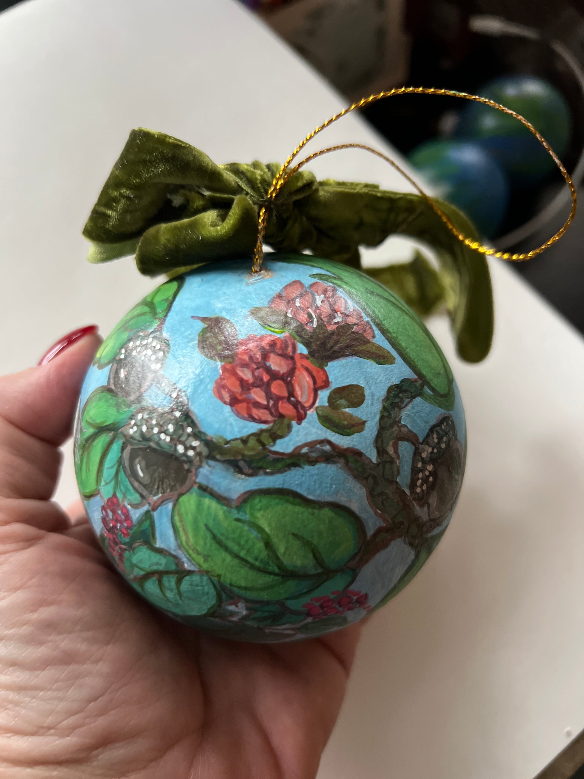 Decorative ornament with floral design held by a hand on a white surface