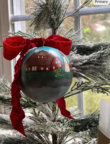 Decorative Christmas ornament with a red house design on a tree branch.