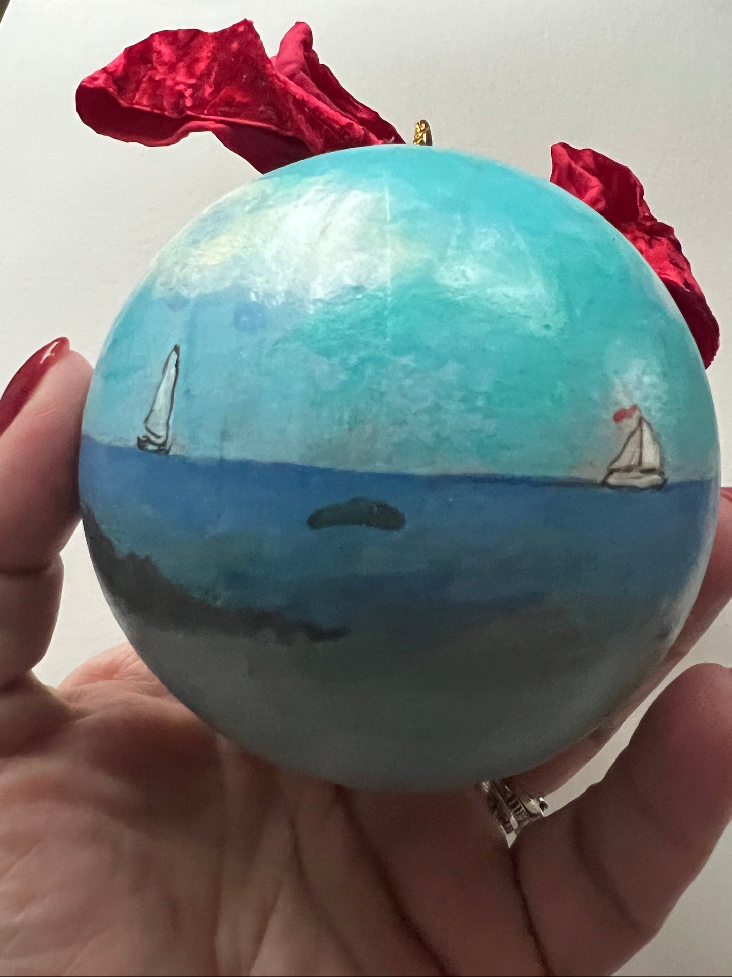 Hand holding a blue and white ball with a red object in the background