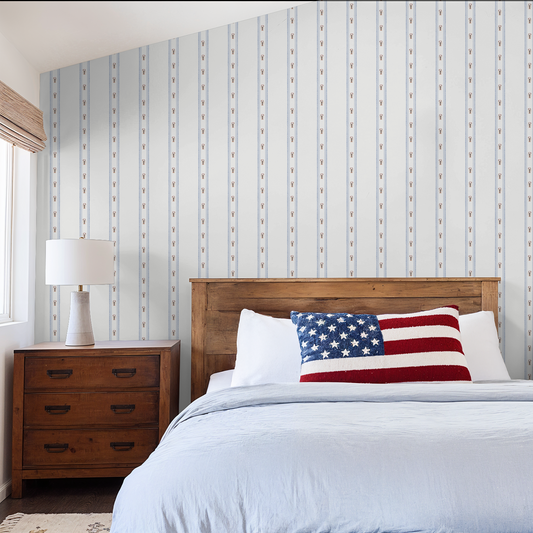Bedroom with wooden headboard, American flag pillow, and striped wallpaper.