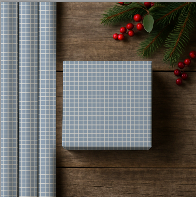 Checkered gift wrap with a roll on a wooden surface, surrounded by red berries and greenery.