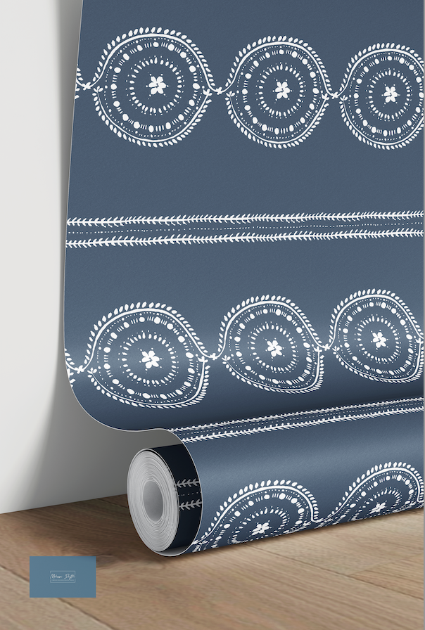 Roll of blue wallpaper with white geometric patterns on a wooden floor.