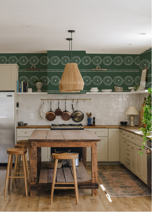 Kitchen with wooden table, stools, and green patterned backsplash.