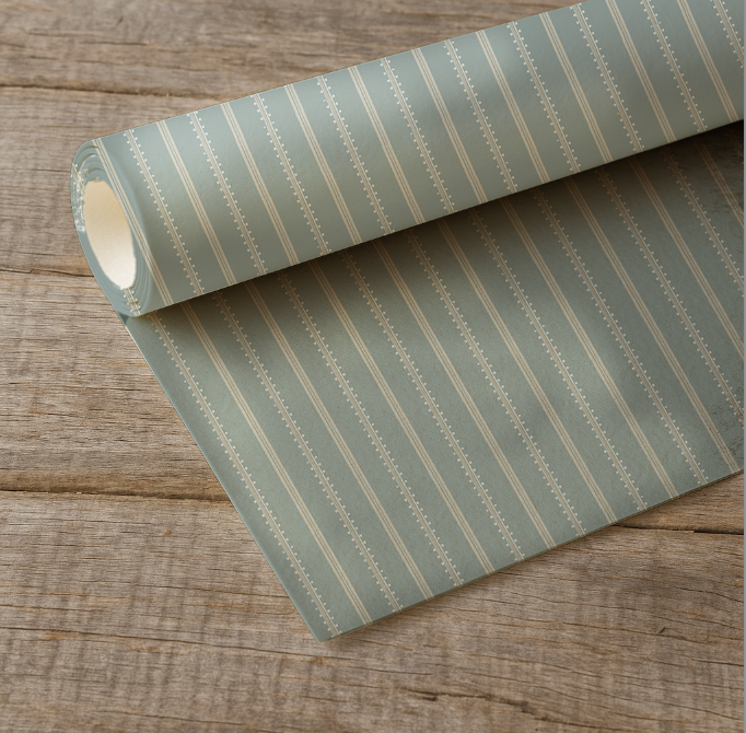 Roll of green striped fabric on a wooden surface