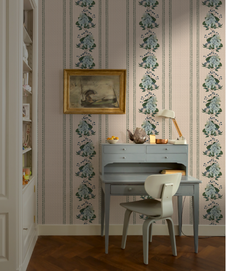 Room interior with a desk, chair, and decorative wallpaper featuring floral patterns.