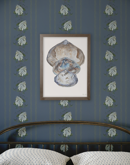 Framed artwork of a shell on a blue wall with floral patterns