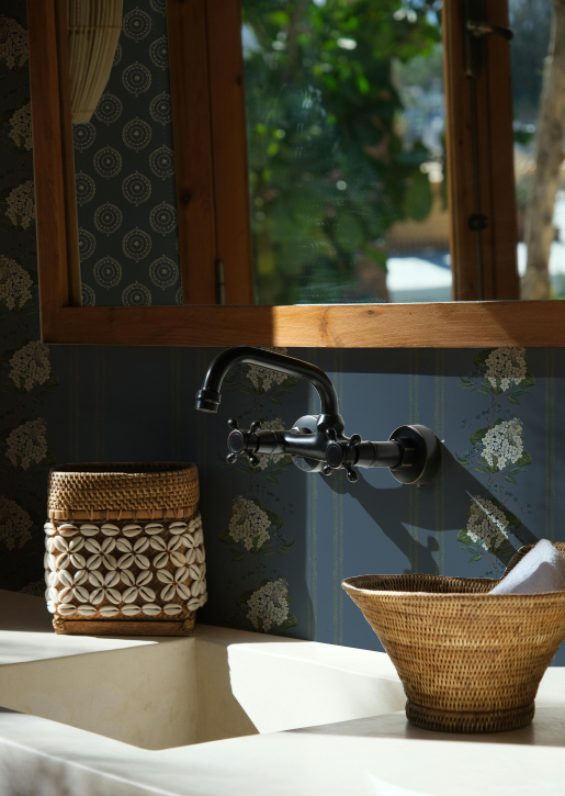Vintage-style bathroom with wicker baskets and a faucet against a patterned wall.