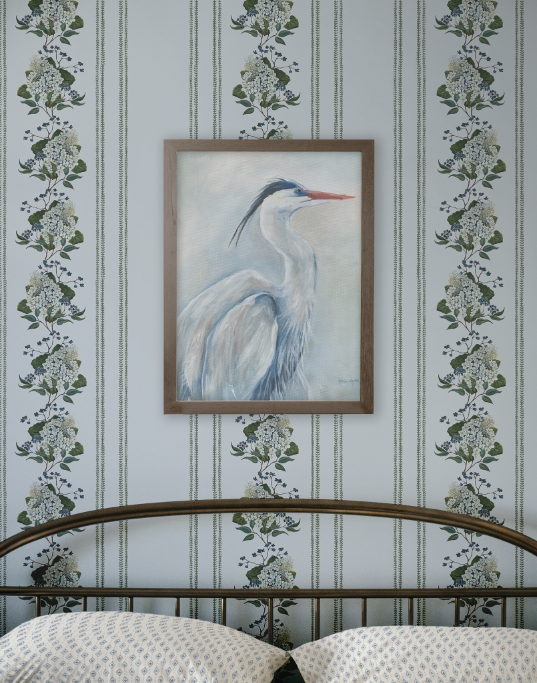 Framed artwork of a heron on a wall with decorative floral and stripe pattern