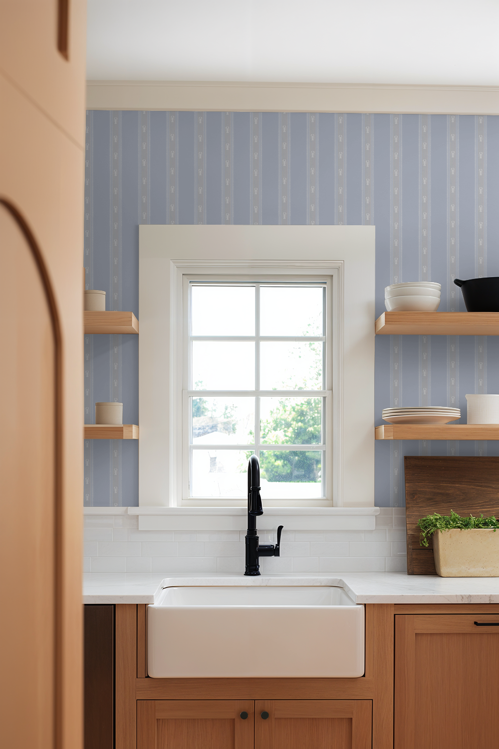 Kitchen with wooden cabinets, white sink, and blue striped wallpaper.