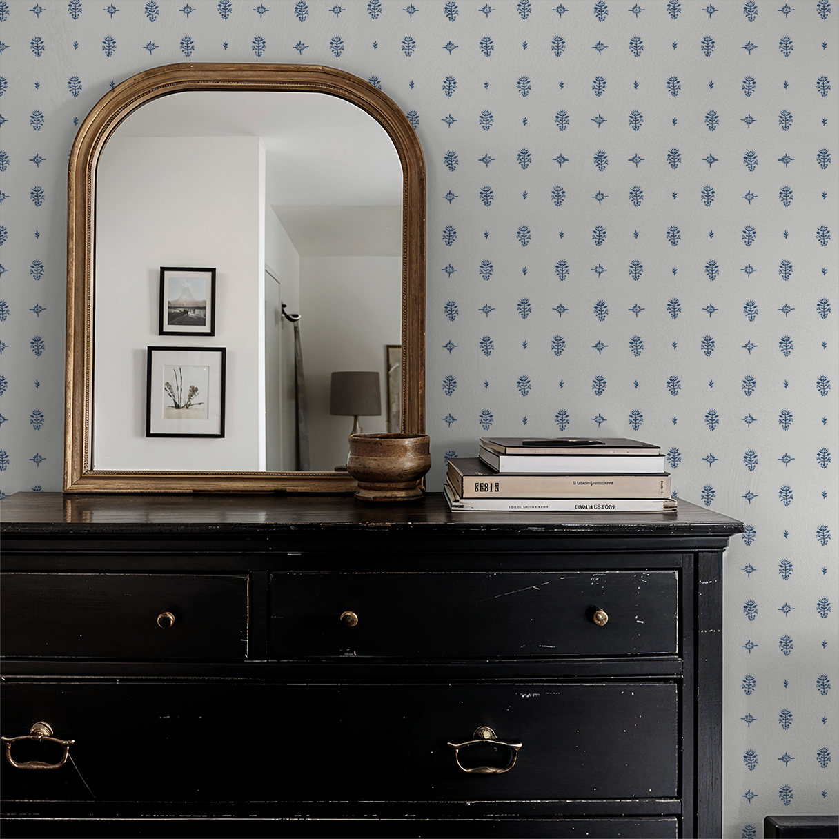 Black dresser with gold mirror and decor against a patterned wall