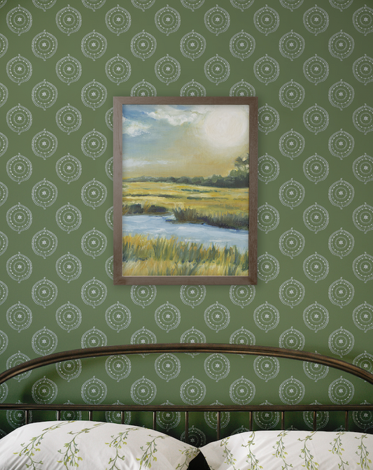 Framed painting of a landscape on a green patterned wall.