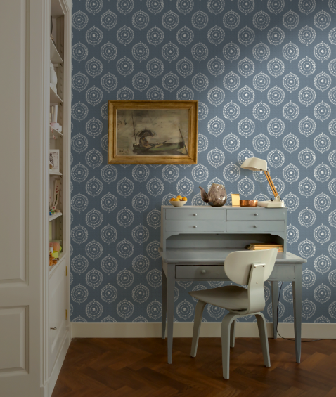Room interior with patterned wallpaper, desk, and chair.