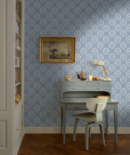 Room interior with a desk, chair, and wall with geometric patterned wallpaper.