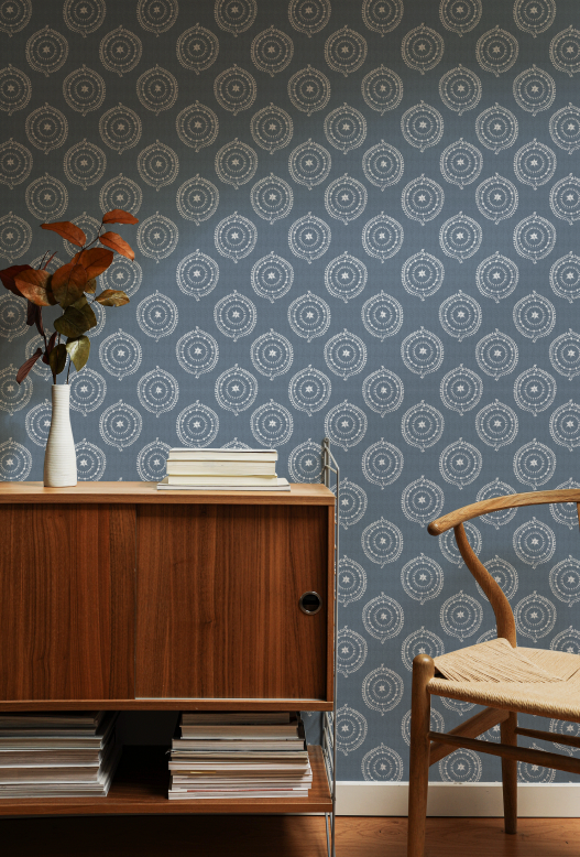 Room interior with a wooden sideboard, chair, and patterned wallpaper.