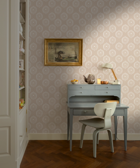 Room interior with a desk, chair, and decorative items against a patterned wall.