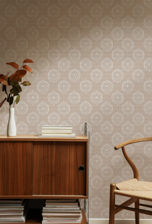 Wooden cabinet with books and a vase against a patterned wall.