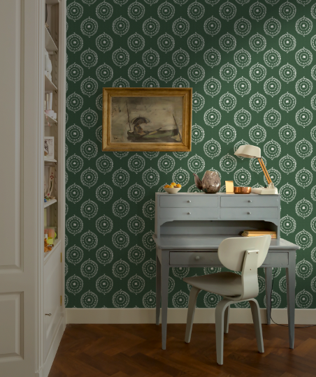 Room interior with green patterned wallpaper, desk, and chair.