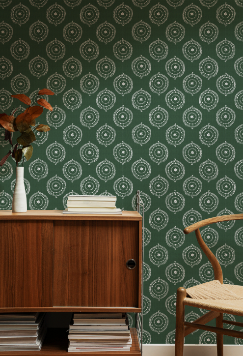 Room interior with green patterned wallpaper, wooden cabinet, and chair.