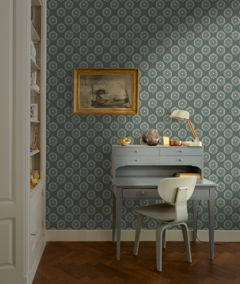 Room interior with a desk, chair, and decorative items against a patterned wall.