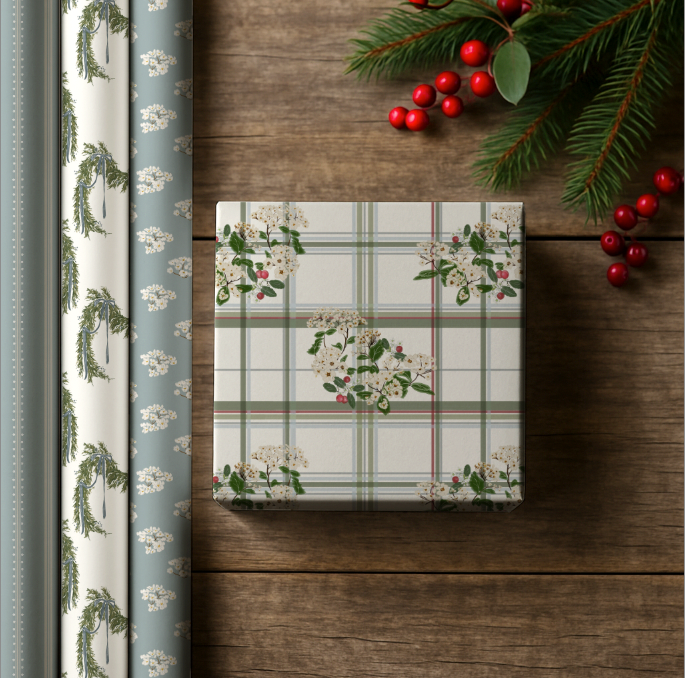 Christmas-themed gift wrap with holly design on a wooden surface