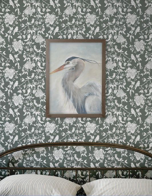 Framed painting of a heron on a wall with floral and bird pattern