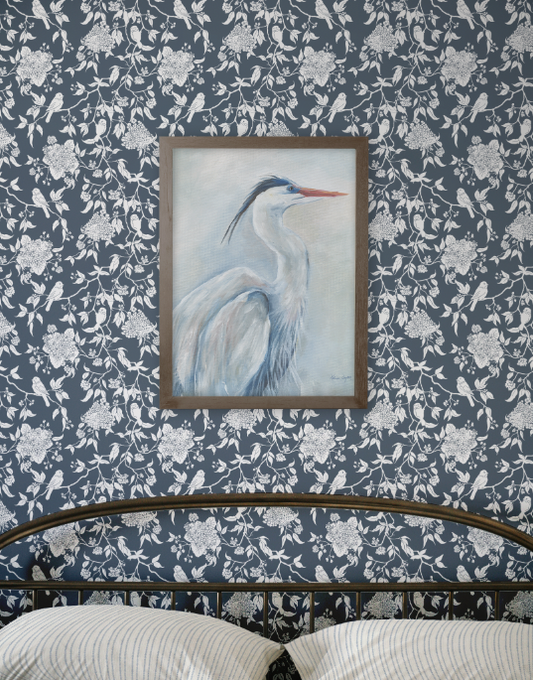 Framed artwork of a heron on a floral-patterned wall.
