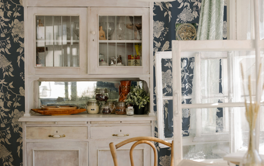 Vintage-style kitchen with floral wallpaper and wooden furniture