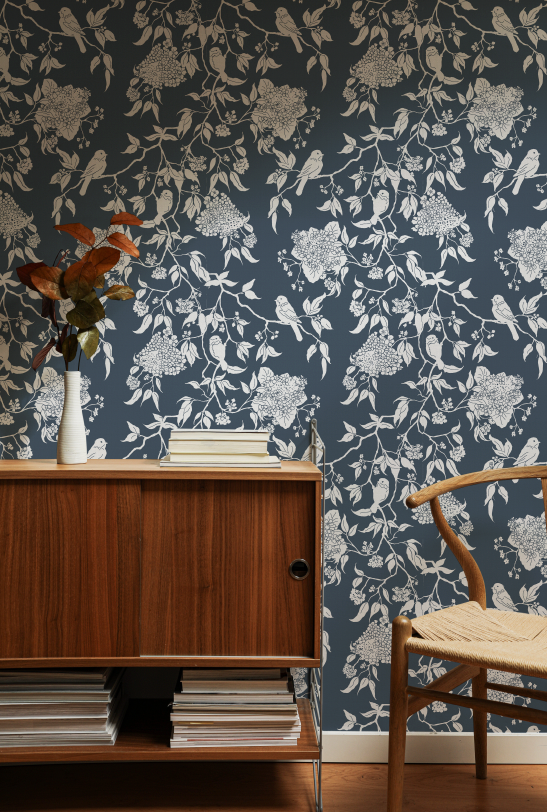 Room interior with floral wallpaper, wooden cabinet, and chair.